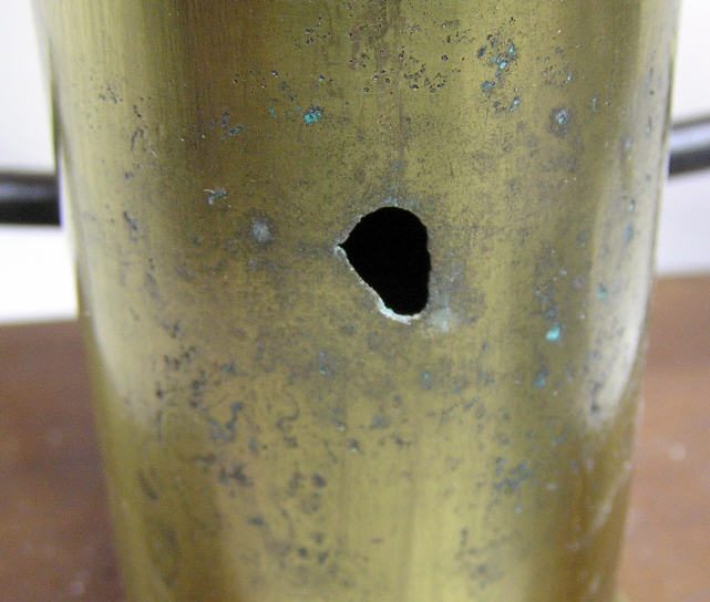 A brass Bulle battery column with a hole corroded right through it